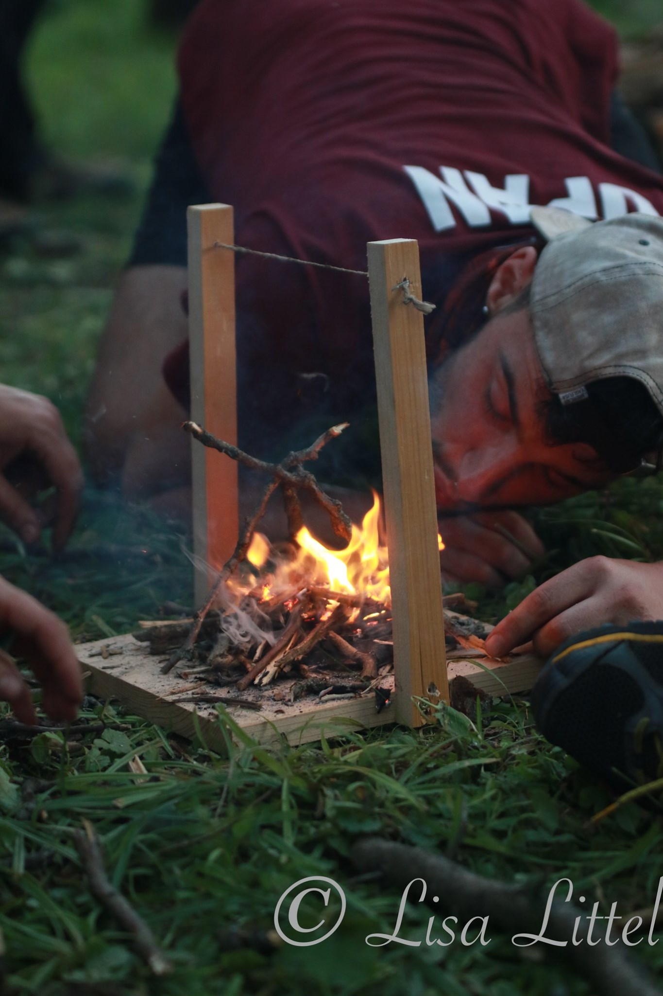 Man with maroon shirt blowing on fire